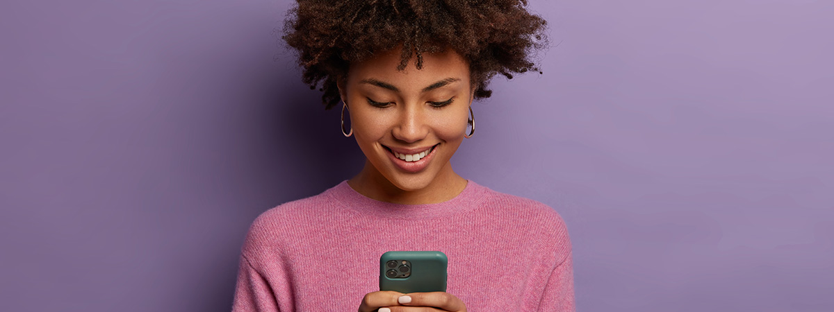 Mujer sonriendo y viendo la pantalla de su celular