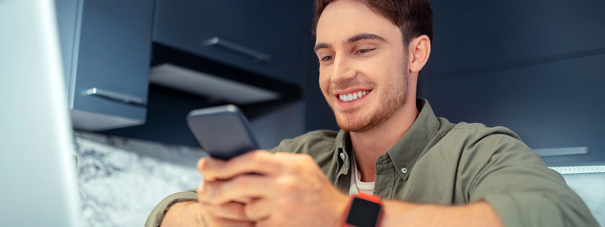 Hombre sonriendo con un celular en su mano.